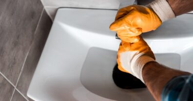 plumber holding plunger in sink with water